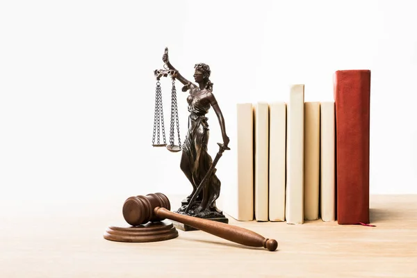 Metal figurine with scales of justice, brown gavel and books on wooden table isolated on white — Stock Photo