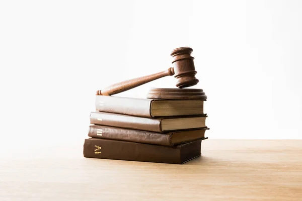 Wooden gavel on pile of brown books on wooden table isolated on white — Stock Photo