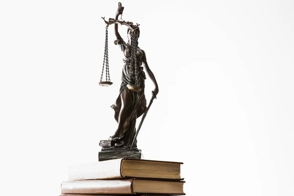 Bronze figurine with scales of justice on pile of brown books isolated on white — Stock Photo