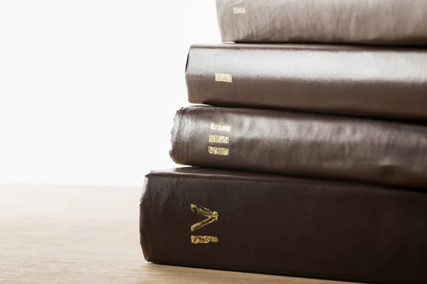 Volumes of old books in leather brown covers on wooden table isolated on white — Stock Photo