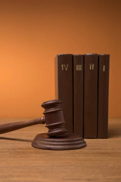 Volumes of brown books in leather covers and gavel on wooden table — Stock Photo