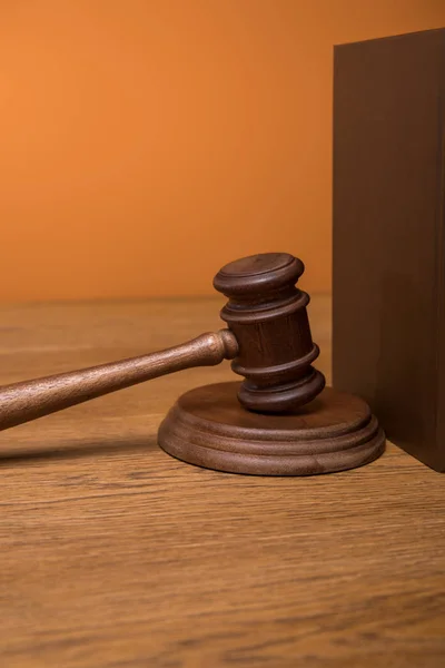 Close up of brown book in leather cover and gavel on wooden table isolated on orange — Stock Photo