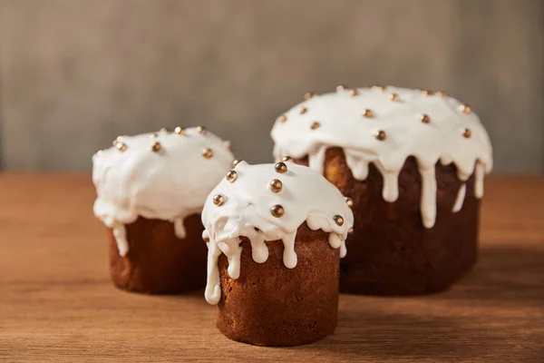 Delicious easter cakes with sprinkles and frosting on wooden table — Stock Photo