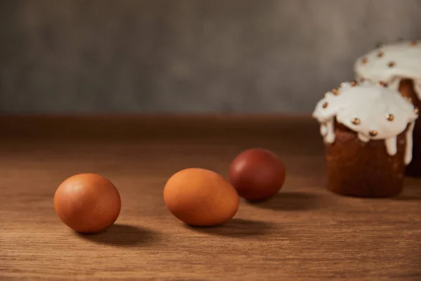 Selective focus of painted chicken eggs and easter cakes on wooden surface with copy space — Stock Photo