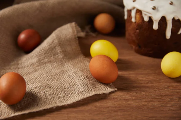 Painted chicken eggs and traditional easter cake decorated with sprinkles on sackcloth — Stock Photo