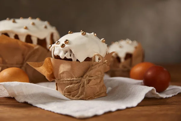 Huevos de pollo pintados y deliciosos pasteles de Pascua decorados con glaseado y espolvoreos en la servilleta - foto de stock