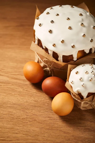 Delicious easter cakes with sprinkles and painted chicken eggs on wooden surface — Stock Photo