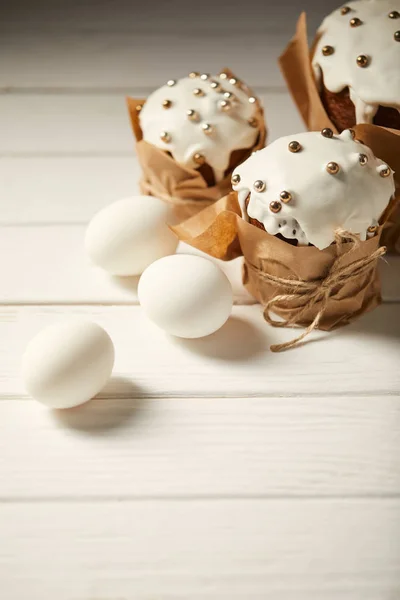 Tortas tradicionales de Pascua con huevos de pollo en la superficie de madera blanca - foto de stock