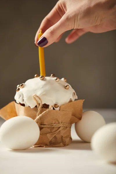 Vista recortada de la mujer poniendo vela en pastel de Pascua con aspersiones - foto de stock