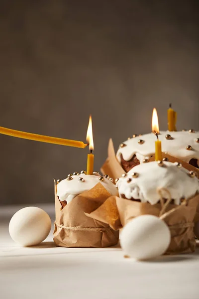 Délicieux gâteaux de Pâques avec des bougies brûlantes et des œufs de poulet sur table blanche — Photo de stock