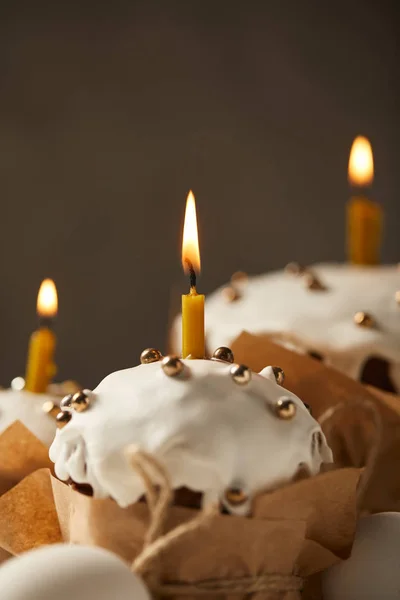 Selective focus of traditional easter cakes with sprinkles and burning candles — Stock Photo