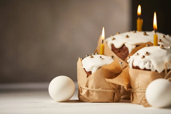 Gâteaux de Pâques traditionnels avec des bougies allumées et des œufs de poulet sur table blanche avec espace de copie — Photo de stock