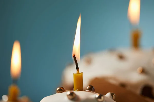 Primer plano de pastel de Pascua decorado con chispas y vela encendida sobre turquesa - foto de stock