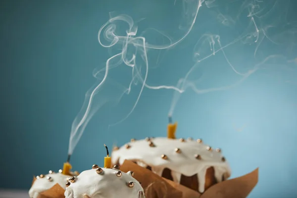 Вибірковий фокус прикрашених великодніх тортів зі свічками та димом на бірюзовому — стокове фото