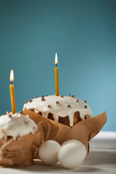 Gâteaux de Pâques avec des bougies et des œufs de poulet sur turquoise avec espace de copie — Photo de stock