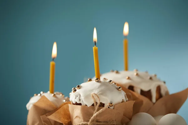 Foco selectivo de pasteles de Pascua decorados con chispas y velas encendidas en turquesa - foto de stock