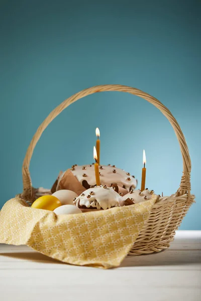 Easter cakes with chicken eggs and napkin in wicker basket on turquoise — Stock Photo