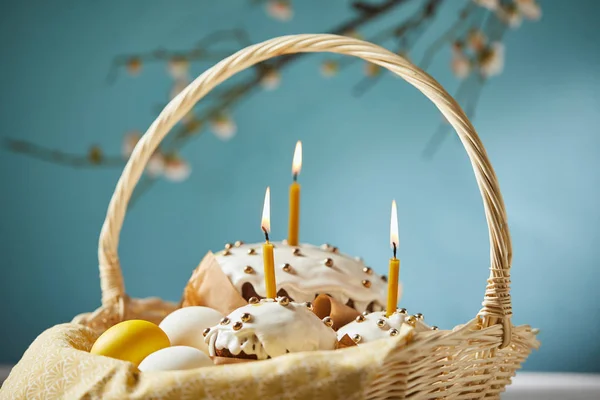 Foco selectivo de pasteles de Pascua con huevos de pollo y servilleta en canasta de mimbre en turquesa - foto de stock