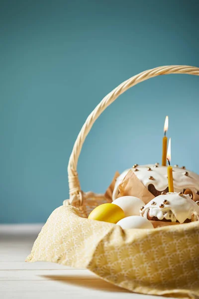Easter cakes with chicken eggs and napkin in wicker basket on turquoise with copy space — Stock Photo
