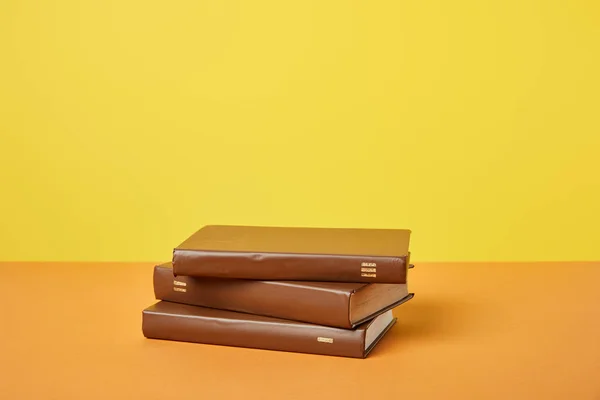 Livres bruns sur surface orange vif isolés sur jaune — Photo de stock