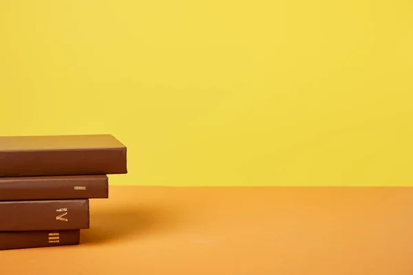 Brown books on bright orange surface isolated on yellow — Stock Photo