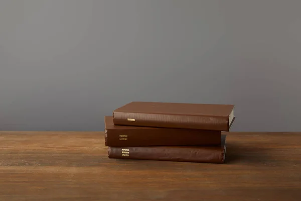 Three brown books on textured wooden surface on grey — Stock Photo