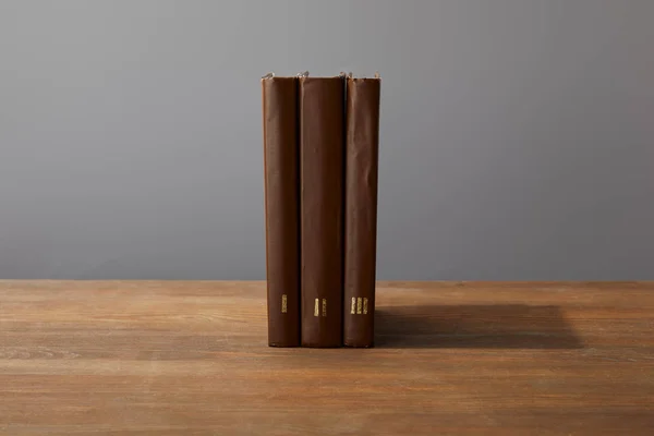Brown books on textured wooden surface isolated on grey — Stock Photo