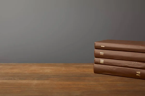 Four brown books on textured wooden surface on grey — Stock Photo