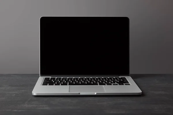 Laptop with blank screen on dark textured surface on grey — Stock Photo