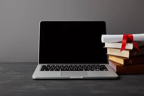 Laptop com tela em branco, diploma e livros isolados em cinza — Fotografia de Stock
