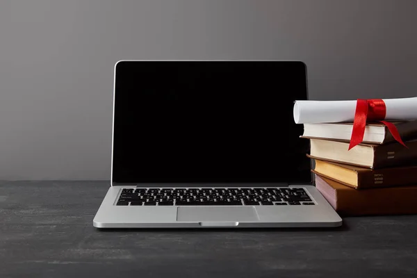 Laptop with blank screen, diploma and books isolated on grey — Stock Photo