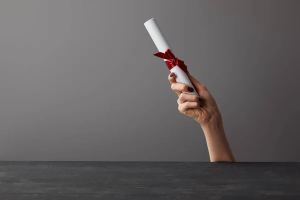 Ausgeschnittene Ansicht einer Frau mit Diplom mit roter Schleife auf grau — Stockfoto