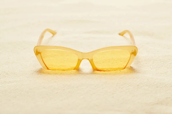 Foyer sélectif de lunettes de soleil jaunes dans la plage de sable fin en été — Photo de stock