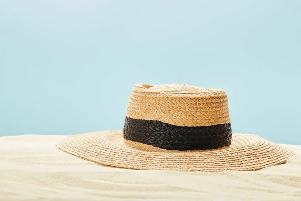 Enfoque selectivo de sombrero de paja en la playa de arena en verano aislado en azul - foto de stock
