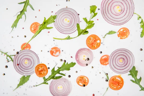 Fondo con tomates en rodajas, cebollas rojas, hojas de rúcula y especias - foto de stock