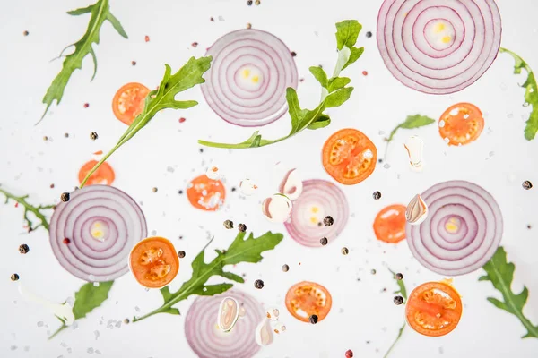 Fondo con tomates en rodajas, cebollas rojas, ajo, hojas de rúcula verde y especias - foto de stock