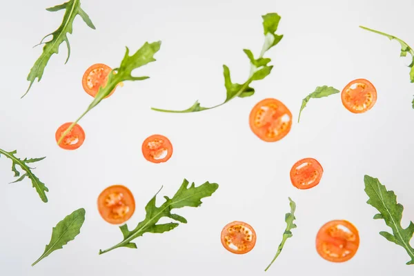 Tomates vermelhos fatiados frescos e folhas verdes de arugula sobre fundo cinzento — Fotografia de Stock