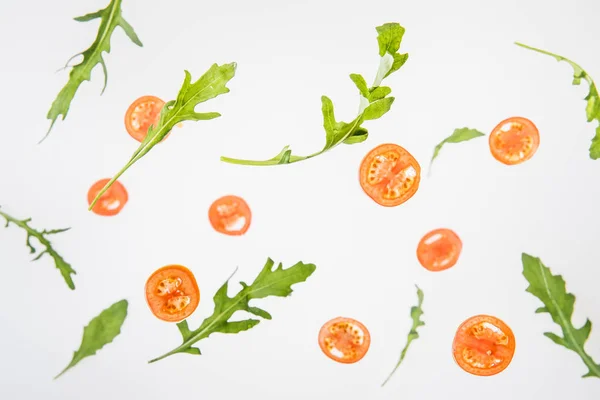 In Scheiben geschnittene rote Tomaten und grüne Rucolablätter auf grauem Hintergrund — Stockfoto