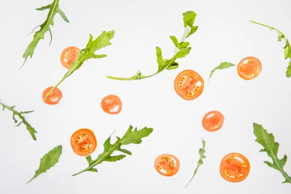 Rodajas de tomates rojos y hojas de rúcula verde sobre fondo gris - foto de stock