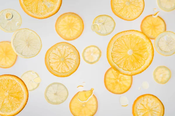 Rodajas de naranja brillante y limón sobre fondo gris con burbujas de agua - foto de stock
