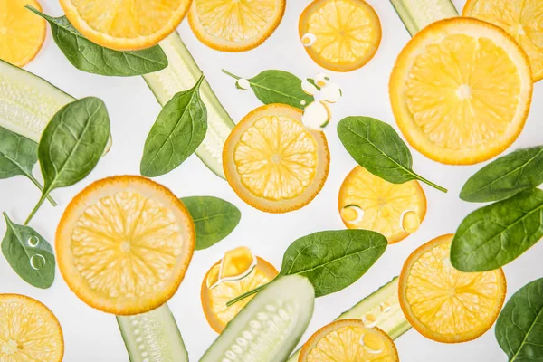 Orange slices with green spinach leaves and cucumbers on grey background — Stock Photo