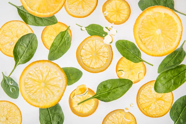 Rebanadas de naranja jugosas con hojas de espinaca verde sobre fondo gris - foto de stock