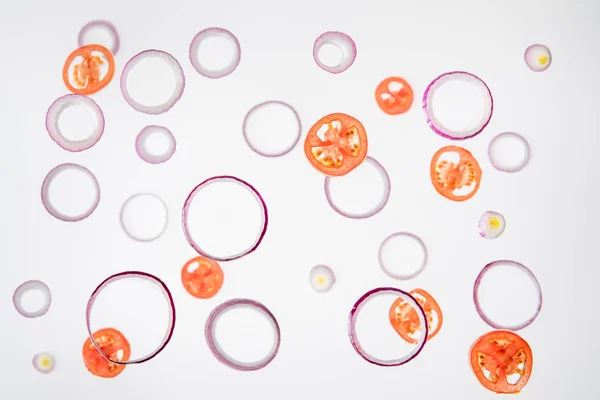 Background with sliced tomatoes and red onions on grey — Stock Photo