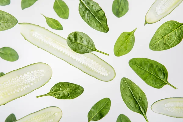 Background with fresh spinach leaves and sliced cucumbers on grey — Stock Photo