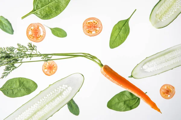 Cetrioli affettati, pomodori, carote e foglie di spinaci su fondo grigio — Foto stock