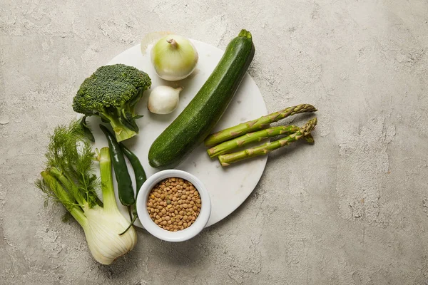 Vista superior de verduras y semillas en superficie texturizada gris - foto de stock