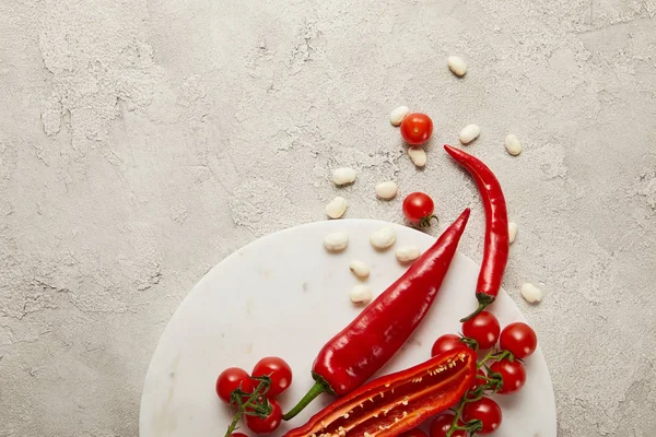 Draufsicht auf Chilischoten, Kirschtomaten und Bohnen auf strukturierter Oberfläche — Stockfoto