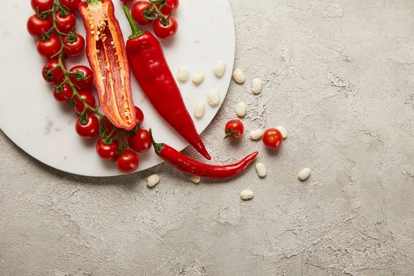 Draufsicht auf Chilischoten, Kirschtomaten und Bohnen auf strukturierter Oberfläche — Stockfoto