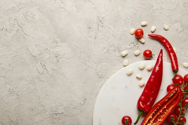 Top view of cherry tomatoes, chili peppers and beans on textured surface — Stock Photo