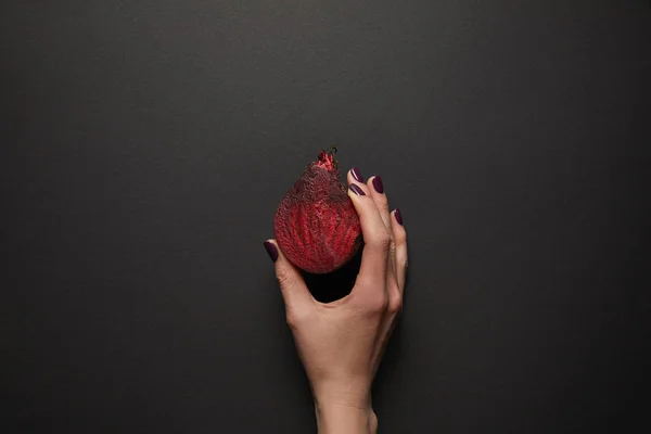 Teilansicht einer Frau, die geschnittene Rüben auf schwarzer Oberfläche hält — Stockfoto
